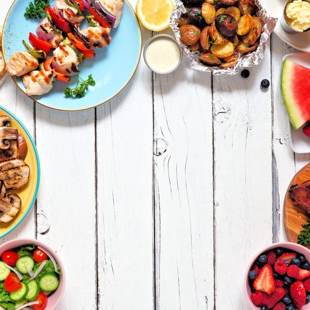 Summer BBQ or picnic food frame over a white wood background summer bbq or picnic food frame variety of grilled meats, vegetables, fruits, salad and potatoes above view over a white wood background copy space