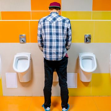 young man in the public toilet, standing next to the urinal in the trade center