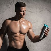 muscular man bodybuilder drinking whey protein or other supplement from a metal shaker