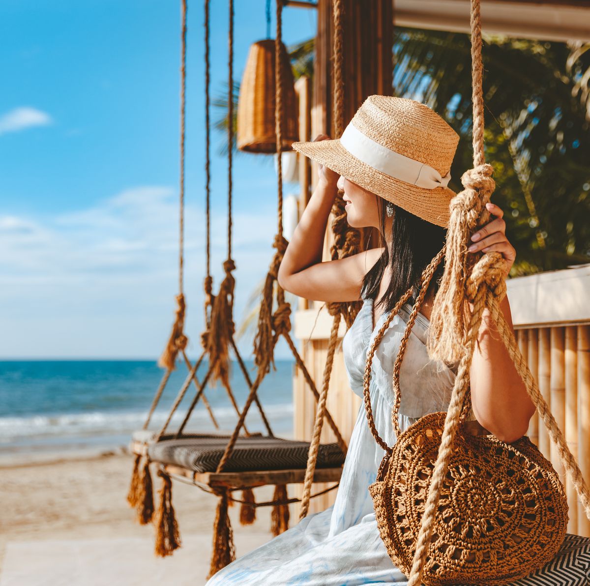 travel summer vacation concept, happy traveler asian woman with hat and dress relax on swing in beach cafe, koh chang, thailand