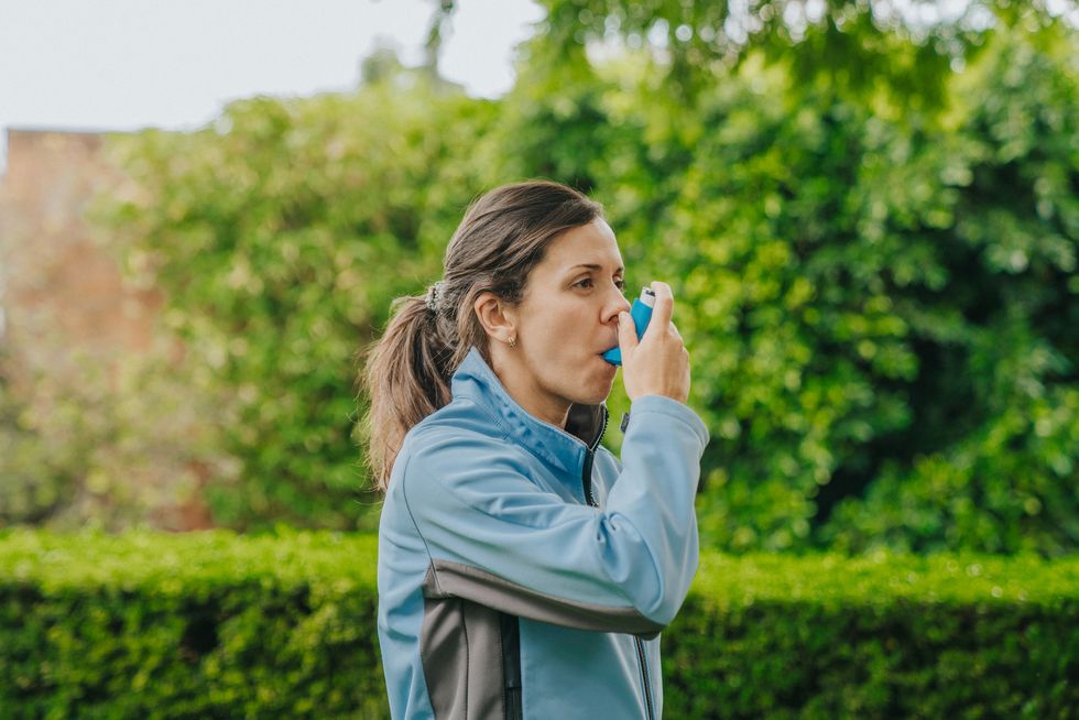 woman using asthma inhaler outdoors