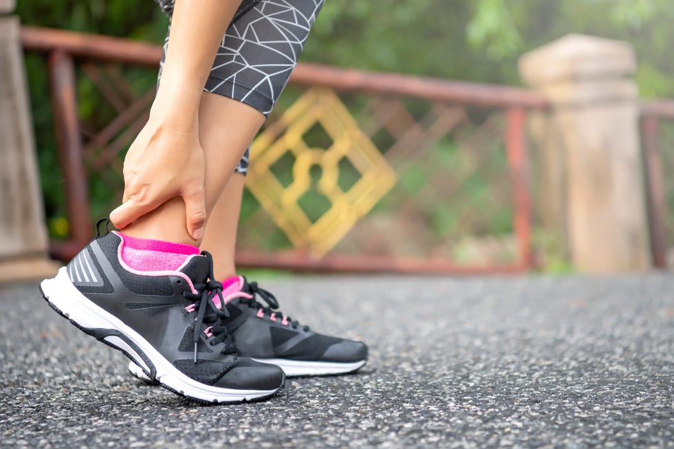 close up asian woman standing on road holds her ankle injury after jogging