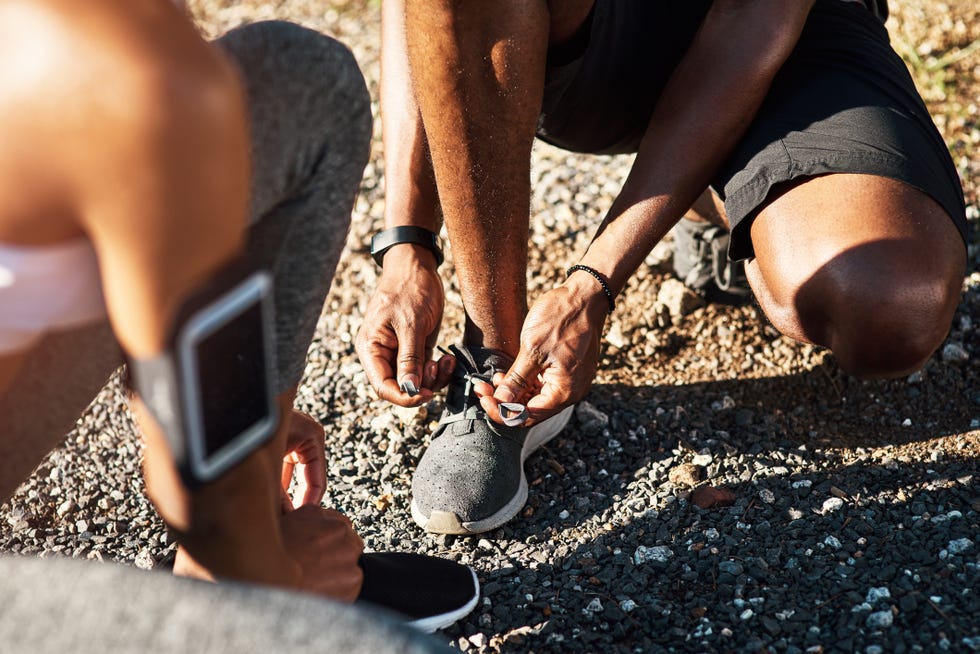 high angle shot of an unrecognizable young couple fastening their shoelaces before beginning their run