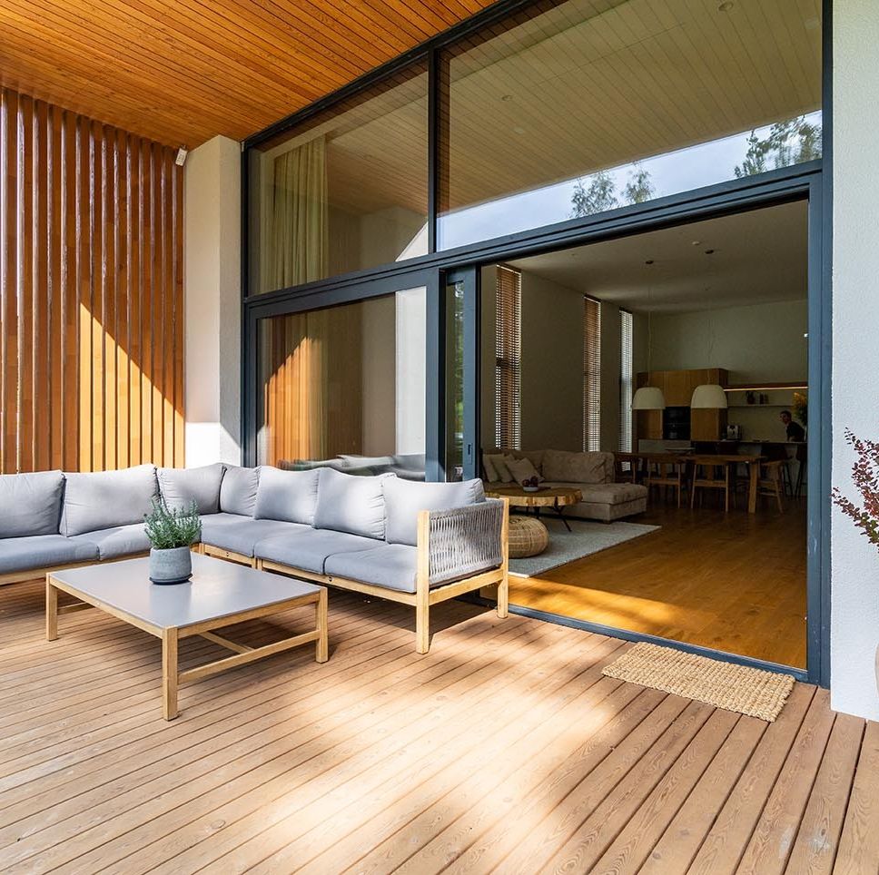 wooden patio connected to a private building, with seating area and cozy lounge zone, open window with entrance to the house