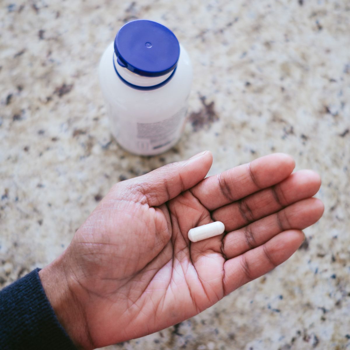 high angle view of unrecognizable black woman holding nutritional supplement in palm of her hand