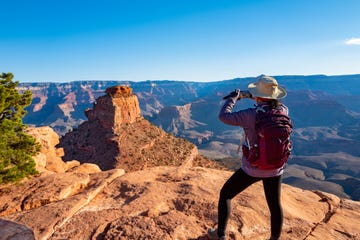 scenic view of the south rim of the grand canyon mature woman on the edge of canyon  taking a photo with smartphone