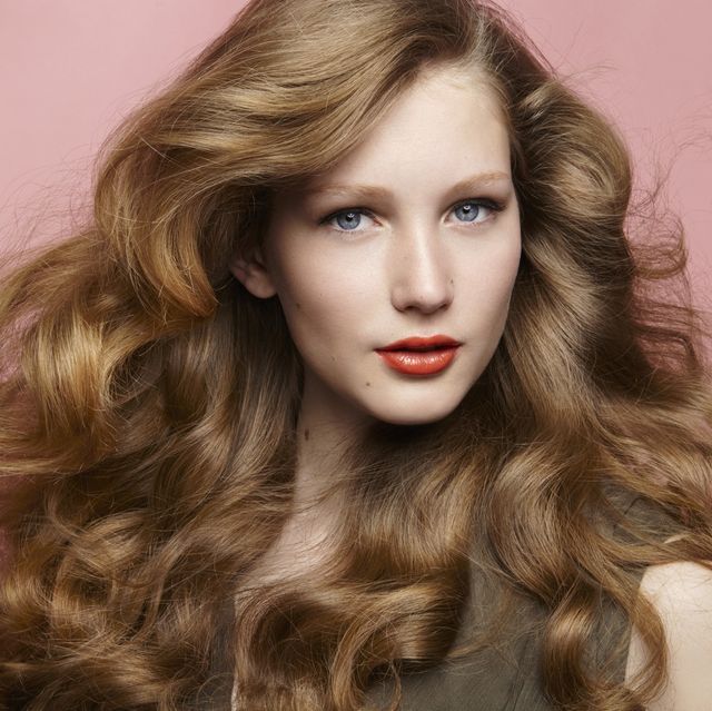 beauty shot of a brunette wearing professional hair and make up in front of a dark background