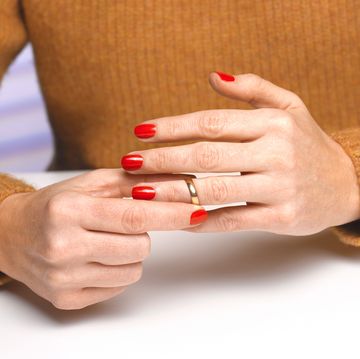 sad young lady removing her wedding ring after divorce decision