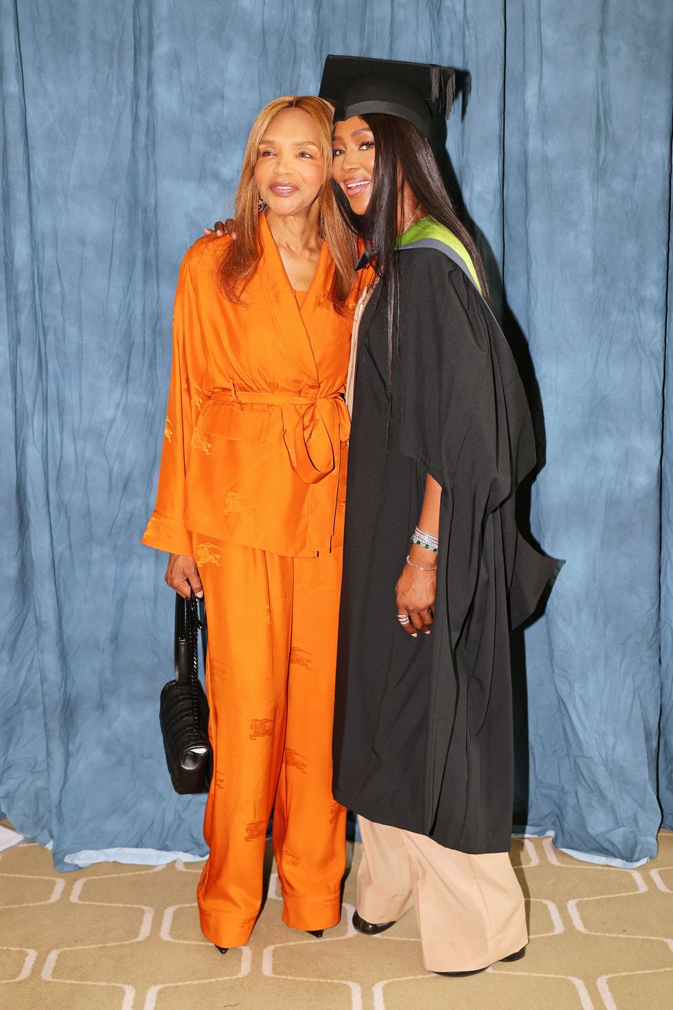 london, england   july 07 valerie morris and naomi campbell celebrate naomi campbell officially became dr naomi campbell as she was formally awarded an honorary phd from the university for the creative arts in recognition of her contribution to the global fashion industry the doctorate was presented to her at the graduation of uca epsom students at the royal festival hall on july 7, 2022 in london, england for the ceremony, naomi wore a burberry biscuit colour wool tailored jacket with orange lapels, waistcoat, and a beige jumpsuit, with biscuit colour leather boots make up by pat mcgrath labs photo by david m benettdave benettgetty images for burberry  outside org