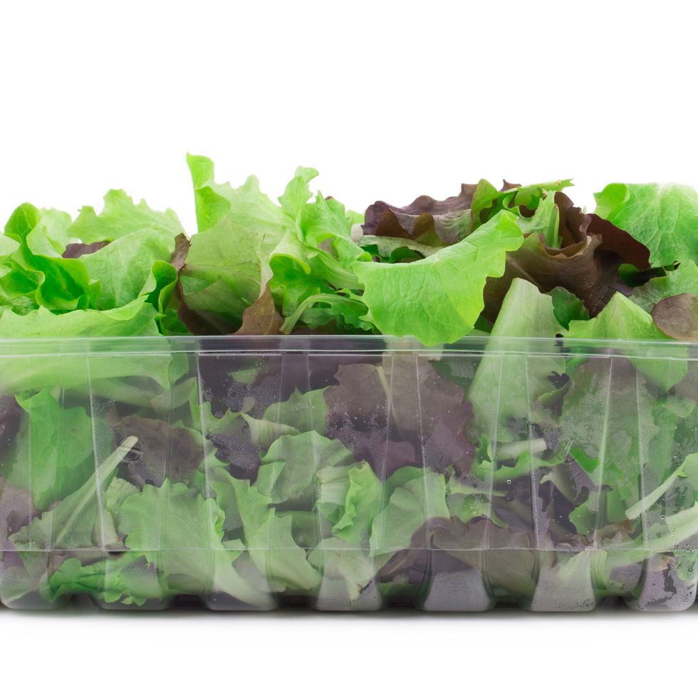 mesclun salad in a plastic box isolated over white background close up