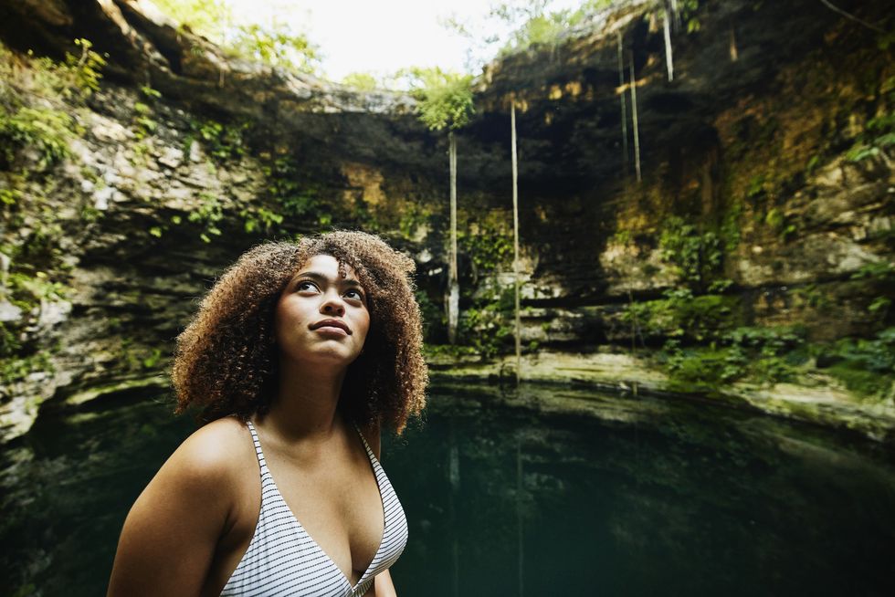 woman looking around cenote before going swimming