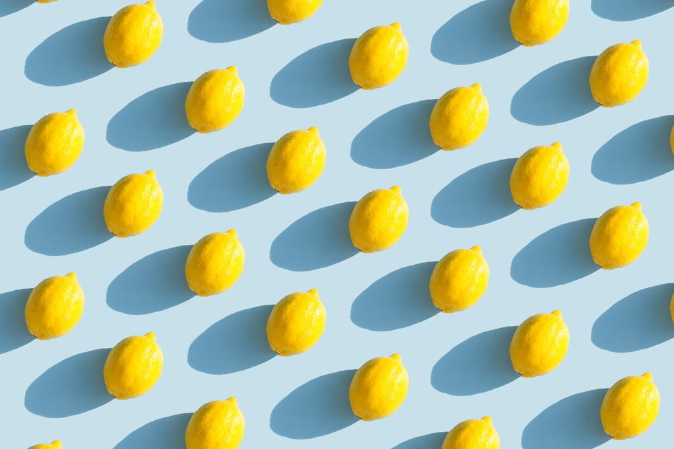 colorful fruit pattern of fresh yellow lemons on blue background with shadows fruit concept flat lay, top view