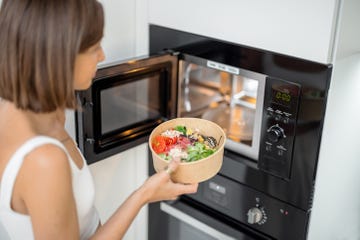 woman heating food with microwave machine at home, female using modern kitchen appliances