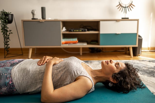 a woman lies on yoga mats and does breathing exercises