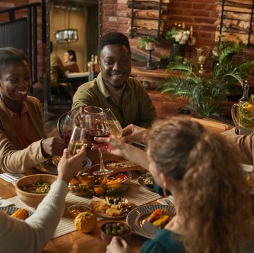 diverse group of people clinking glasses while enjoying dinner