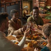 diverse group of people clinking glasses while enjoying dinner