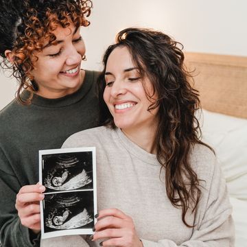lgbt lesbian couple holding ultrasound photo scan of growing baby in pregnancy time   focus on right woman face