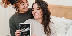 lgbt lesbian couple holding ultrasound photo scan of growing baby in pregnancy time   focus on right woman face