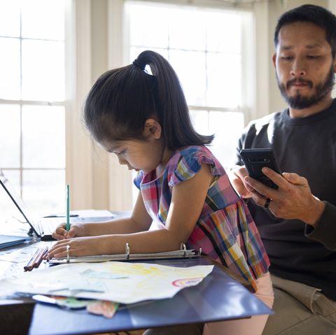 father working from home and helping daughter with schoolwork