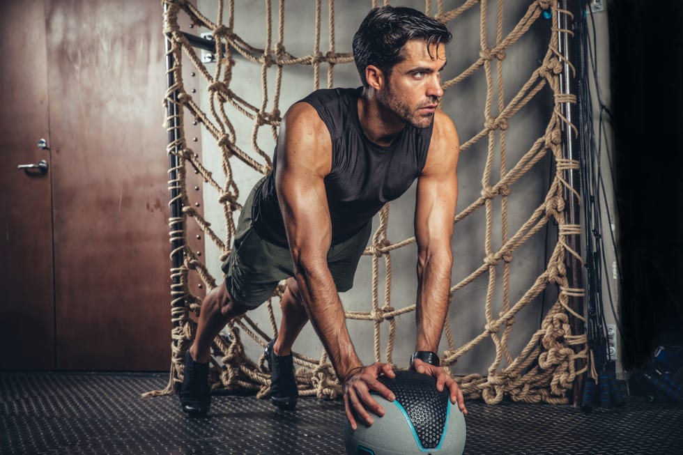 handsome man exercising plank pose on a medicine ball