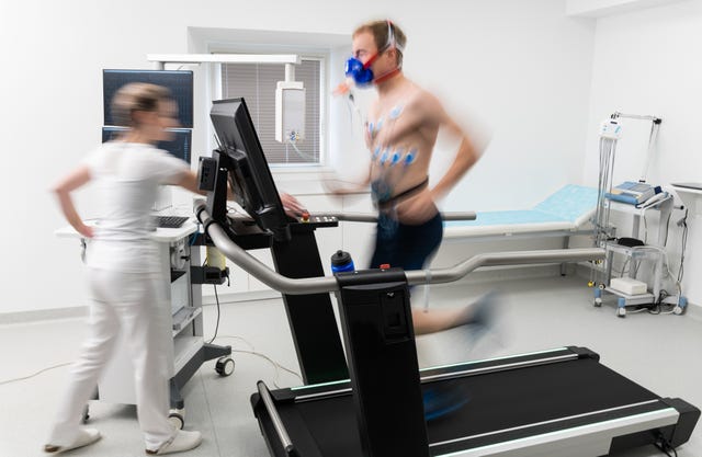 young adult man having a vo2 test with a vo2 mask on his face, electrocardiogram pads attached, treadmill