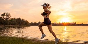 woman trail running by the nature with beautiful lakeside sunset view jogging outdoors in evening mental health, active lifestyle sports background and room for copy space