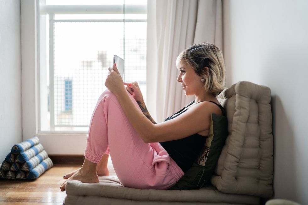 woman sitting on a futon using digital tablet at home