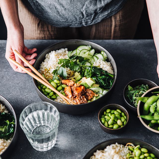 close up of woman eating omega 3 rich salad female having healthy salad consist of chopped salmon, spinach, brussels sprouts, avocado, soybeans, wakame and chia seeds in a bowl