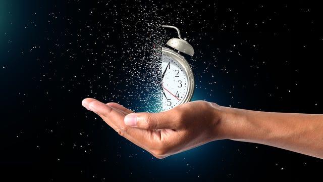 concept of passing away, the clock breaks down into pieces hand holding analog clock with dispersion effect