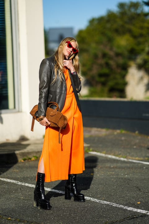 paris, france September 30 a guest wears vintage red sunglasses, a large chain necklace, gold chain pendant, a shiny orange midi dress, a shiny black leather jacket, a brown suede handbag , shiny leather high heel shoes with platform heels, a juste un clou gold ring by cartier, a juste un clou gold bracelet by cartier, a love gold bracelet by cartier, big chain bracelets, gold rings, off coperni , during Paris Fashion Week, Womenswear, Spring Summer 2022, on September 30, 2021 in Paris, France photo by edward berthelotgetty images