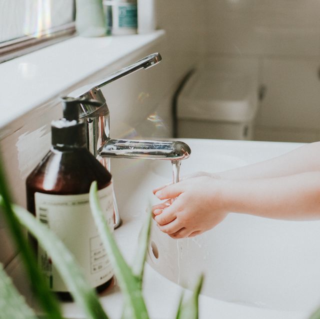 cute little girl washing her hands at a bathroom sink, in a stylish home environment aloe vera plant in foreground and liquid soap and chrome tap featured little girl is confident and content conceptual with space for copy