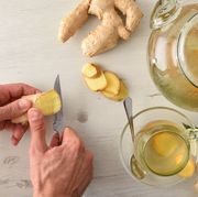 man preparing ginger infusion on a white table with sliced ginger root and teapot top view