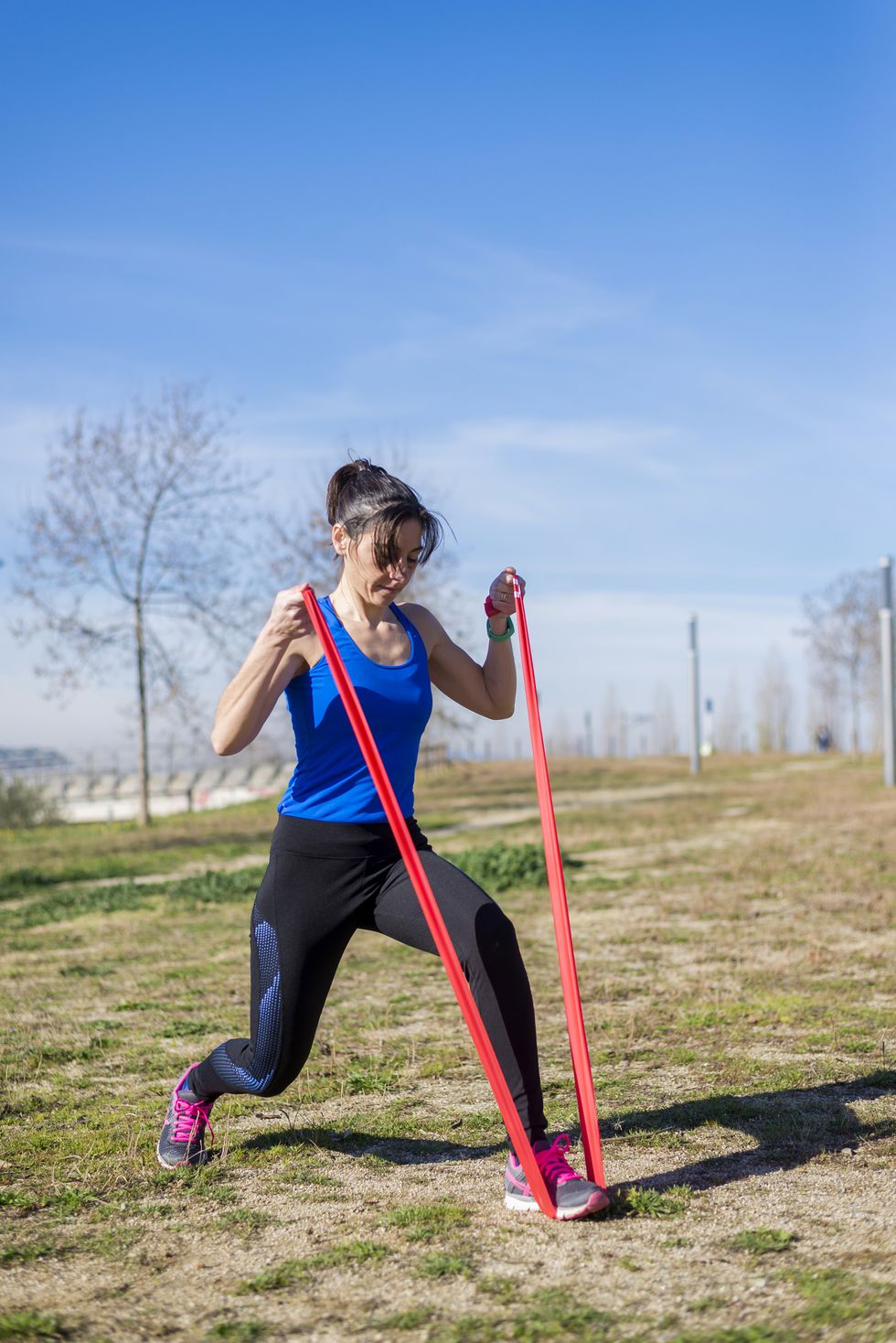 female athlete exercising with resistance  band on grassy field
