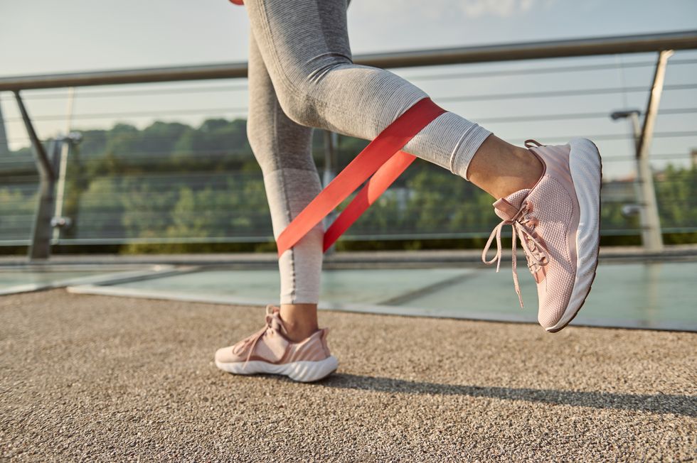 close up of the legs of an athlete woman doing body weight training with a resistance fitness elastic band on a city bridge