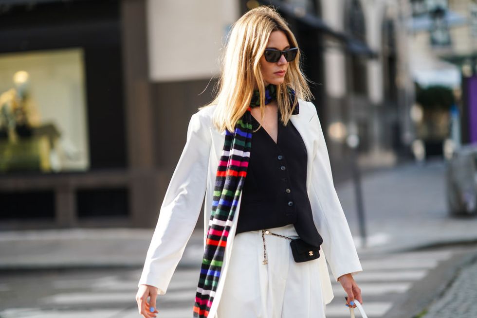 paris, france   march 02 natalia verza aka mascarada wears sunglasses, earrings, a long colored striped scarf, a black vest, a white oversized blazer jacket, a small chanel belt bag, white suit pants, on march 02, 2021 in paris, france photo by edward berthelotgetty images