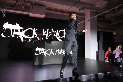 jack harlow on a black stage, in action, holding a mic to his mouth