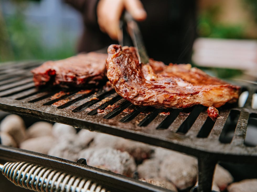 woman doing bbq steaks on a flame grill