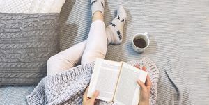 mujer leyendo un libro en la cama con una taza de te