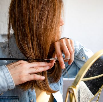 woman cutting own hair with scissors