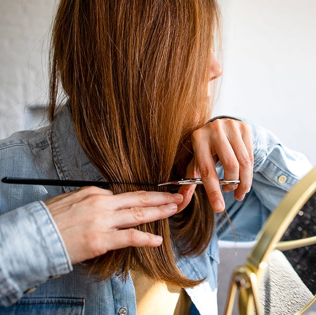 woman cutting own hair with scissors