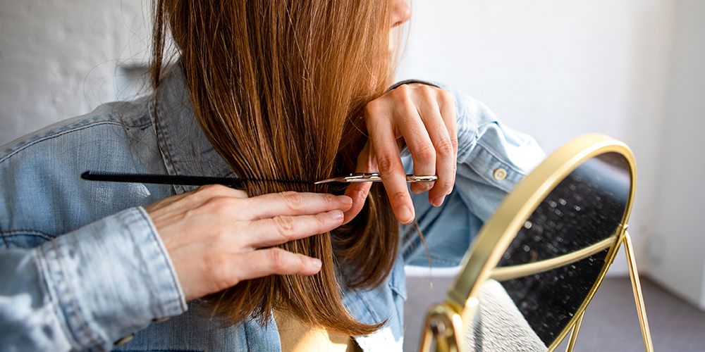 woman cutting own hair with scissors