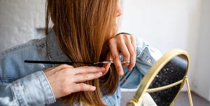 woman cutting own hair with scissors