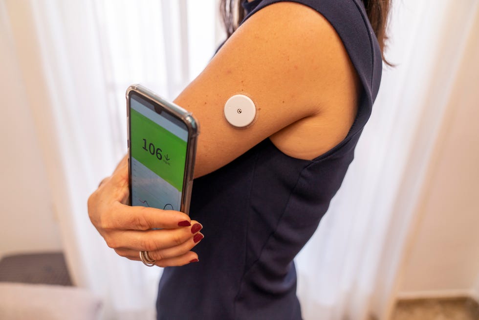 side view of woman checking her blood sugar levels using an smartphone app the app interface is my own design