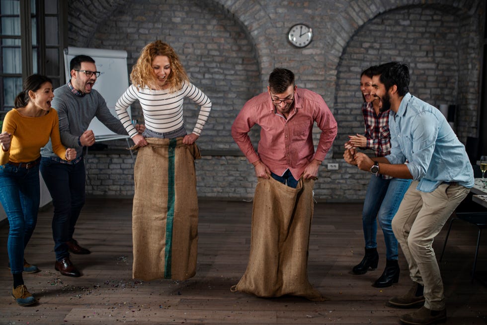 group of happy entrepreneurs having fun on a sack race in the office