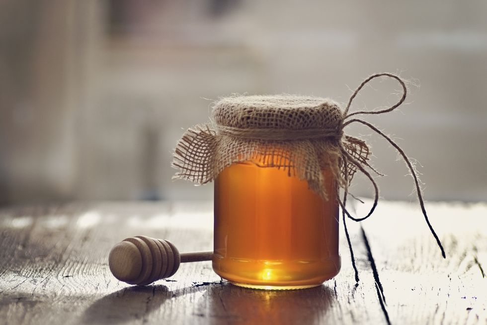 golden honey with honey stick on wooden table