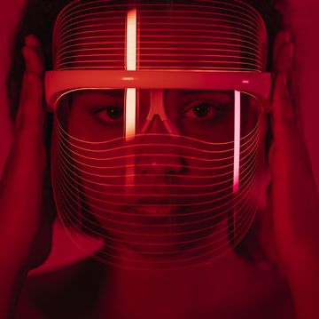 woman wearing red light therapy mask against wall