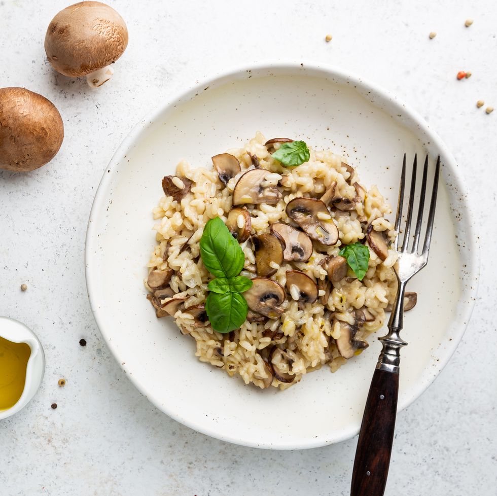 risotto with mushrooms in a white plate over white background, top view