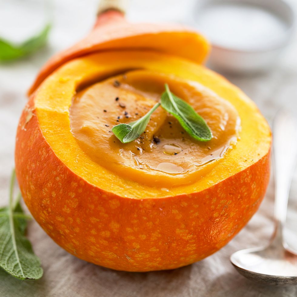 tasty appetizing beautiful pumpkin soup in the whole pumpkin with bread and spices ready to eat on table closeup