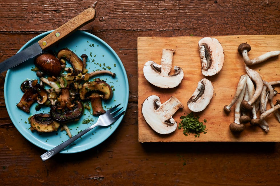 still life of cooked and raw mushrooms on old brown table