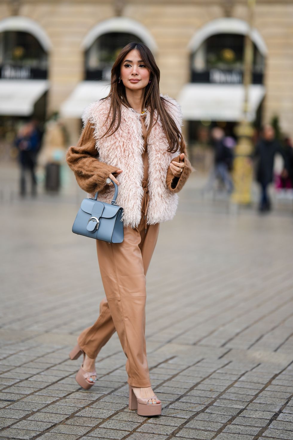 paris, france   september 29 heart evangelista wears a pale pink fluffy sleeveless jacket, a brown ribbed wool cropped pullover, brown shiny leather large pants, a blue gray shiny leather handbag from delvaux, beige shiny varnished leather platform heels shoes , after roger vivier, during paris fashion week   womenswear springsummer 2023, on september 29, 2022 in paris, france photo by edward berthelotgetty images